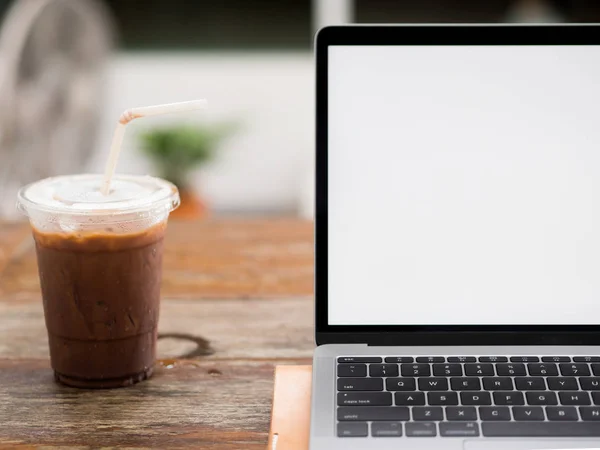 Ноутбук на деревянном столе со льдом кофе в кафе. — стоковое фото