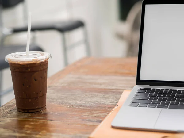 Laptop on wooden desk with iced coffee in the cafe. — Stock Photo, Image