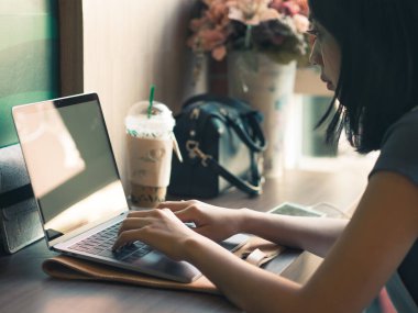 Kadın kahve kafede dizüstü üzerinde çalışıyor.