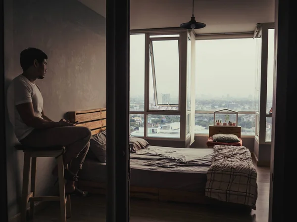 Solitaire et sans esprit homme est assis dans sa chambre à coucher en regardant s — Photo