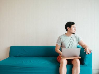 Adam onun rahat bir beze kanepede dizüstü bilgisayar kullanarak.