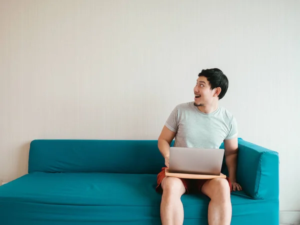 Чоловік використовує ноутбук на дивані в його повсякденній тканині . — стокове фото