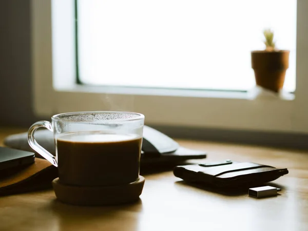 Taza de café caliente en el escritorio de la computadora del espacio de trabajo con poca luz de wi — Foto de Stock