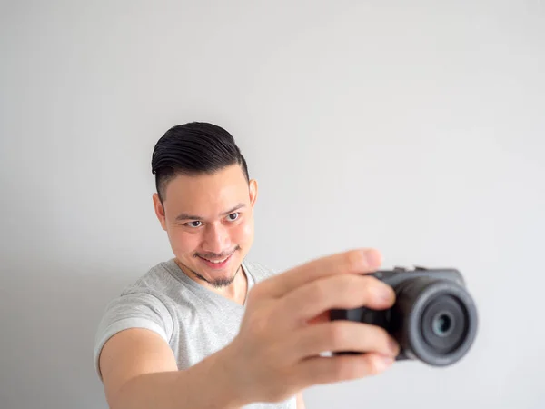 El hombre sostiene una cámara sin espejo y trata de tomar una foto . —  Fotos de Stock