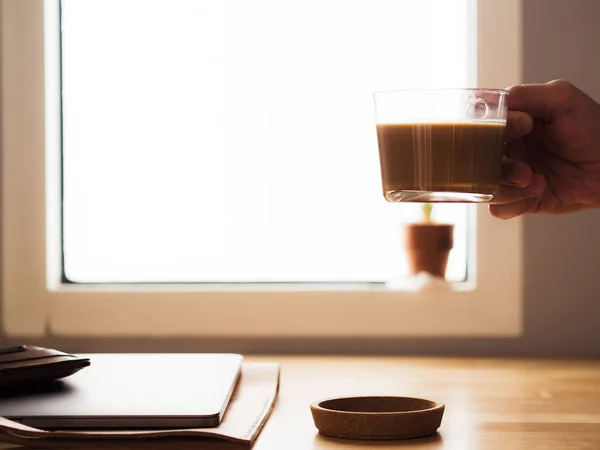 Kaffeetrinken am Schreibtisch mit Laptop am Fenster — Stockfoto