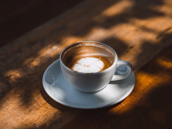 Gelas panas putih kopi Latte di atas meja kayu dalam bayangan bayangan . — Stok Foto