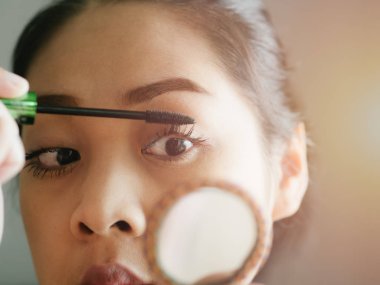 Kadın onun kirpik makyaj maskara koyuyor.