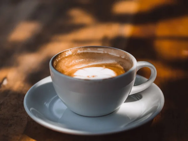 Gelas panas putih kopi Latte di atas meja kayu dalam bayangan bayangan . — Stok Foto