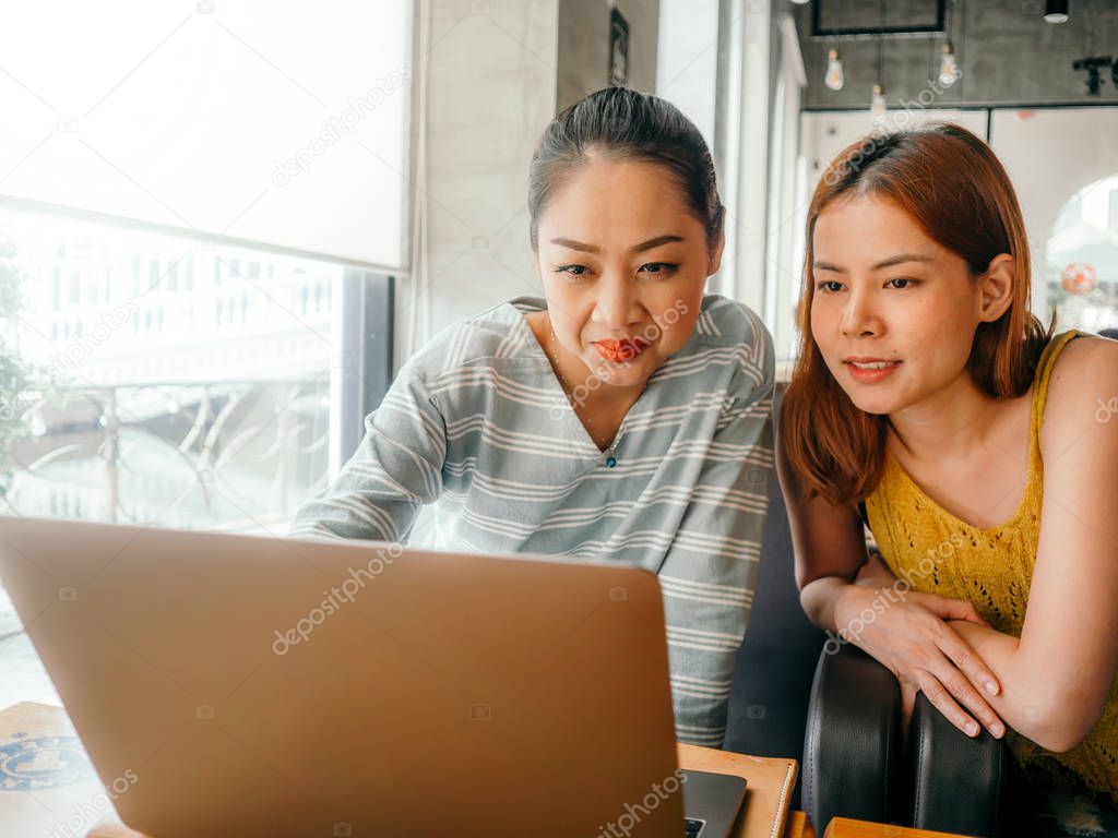 Two girls have some fun checking out the photo work in the lapto