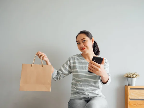 Woman showing off empty paper bag of product she purchased onlin