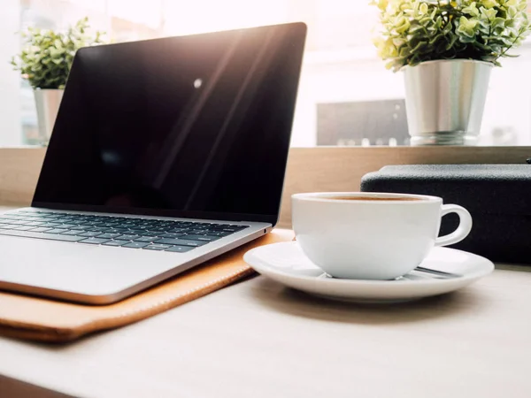 Laptop und eine Tasse Kaffee mit Morgenlicht im Café. — Stockfoto