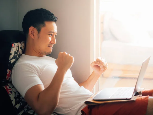 Happy man menggunakan laptop dan bersantai di sofa di pagi hari . — Stok Foto