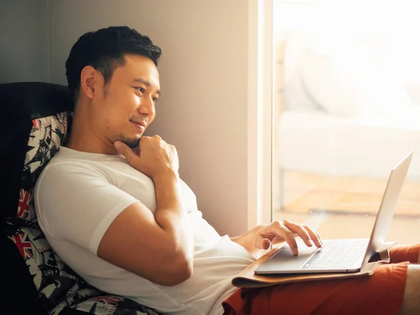 Happy man menggunakan laptop dan bersantai di sofa di pagi hari . — Stok Foto