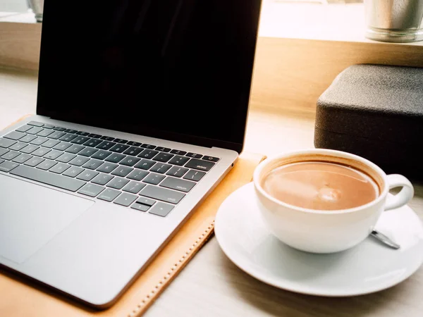 Dizüstü bilgisayar ve bir fincan kahve ile sabah kafede hafif.
