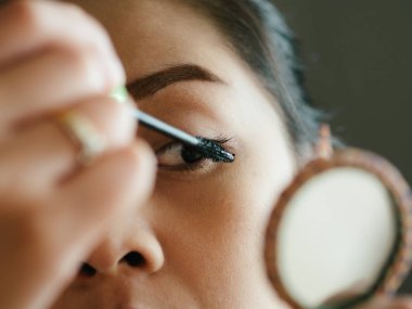Kadın onun kirpik makyaj maskara koyuyor.