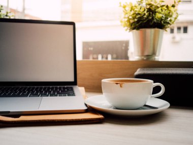 Dizüstü bilgisayar ve bir fincan kahve ile sabah kafede hafif.