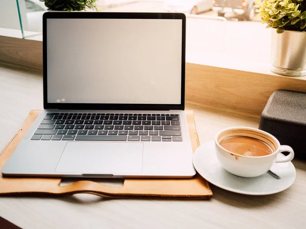 Tazza da caffè su tavolo di legno con computer portatile alla luce del  mattino ia generativa