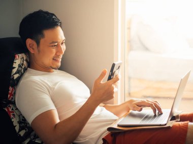 Mutlu bir adam laptop kullanıyor ve sabah koltukta dinlenmek.