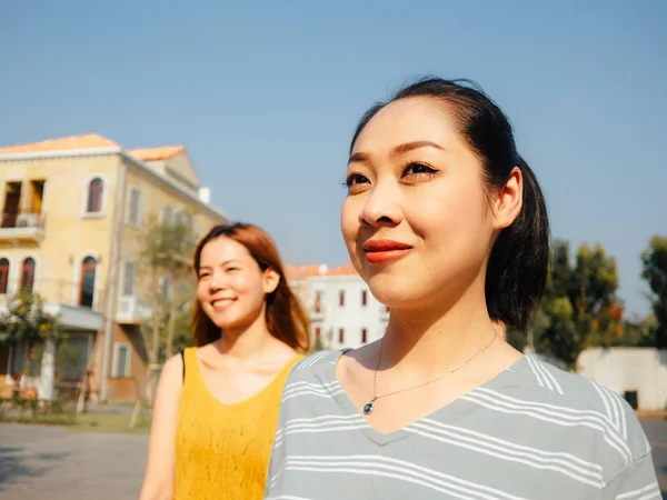 两个亚洲旅游女孩走在城市周围观光与其中一个领先的方式 — 图库照片