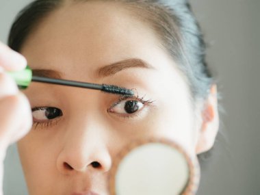 Kadın onun kirpik makyaj maskara koyuyor.