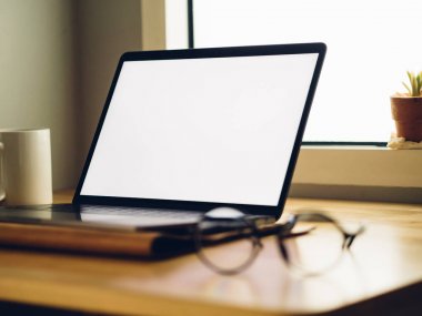Serbest office odasında ahşap masa üzerinde beyaz boş ekran ile dizüstü bilgisayar.