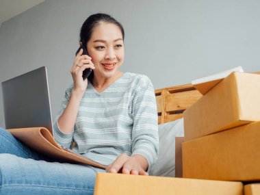 Online iş sahibi Asyalı kadın almak müşteri siparişi ve onun ürün stok kontrol.
