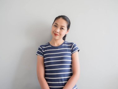 Yorgun ya da sahte gülümseme yüzünü kadının gri arka plan üzerinde.