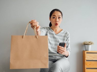 Woman showing off empty paper bag of product she purchased onlin clipart