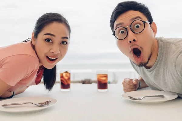 Wow und schockiertes Gesicht des Liebespaares bei einem Date im Restaurant am Strand. — Stockfoto