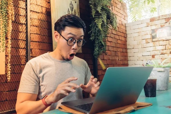 Şok olmuş ve şaşırmış bir adam kafede dizüstü bilgisayarıyla çalışıyor..