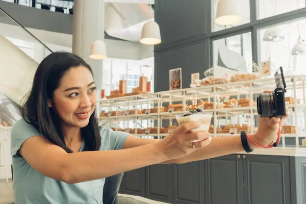 Mutlu kadın kafeteryada kekiyle selfie çekiyor..