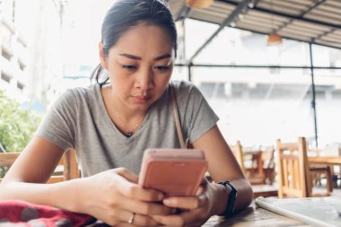 Kadın ciddi yüzlü akıllı telefon kullanıyor..