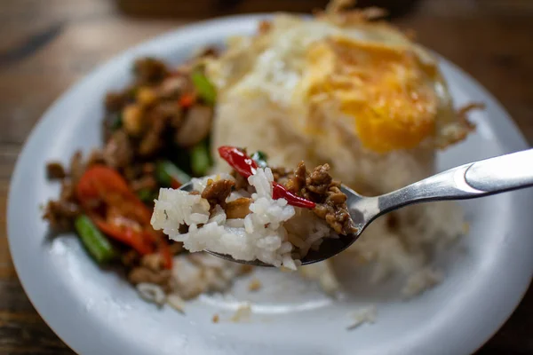 Eating Rice topped with stir-fried beef and basil