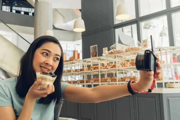 Mutlu kadın kafeteryada kekiyle selfie çekiyor..