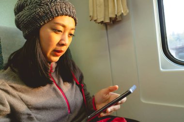 Kadın trene biniyor ve pencereden dışarı bakıyor..