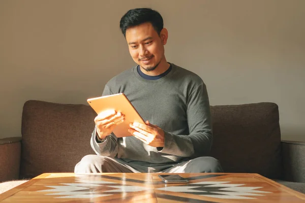 Manusia menggunakan perangkat tablet pintarnya di apartemen ruang tamunya . — Stok Foto