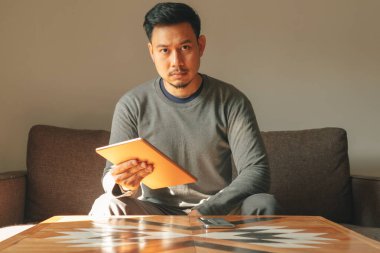 Adam oturma odasında akıllı tablet cihazını kullanıyor..