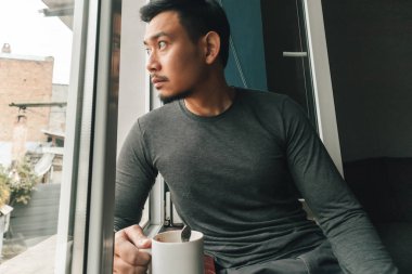 Man is drinking hot coffee and feeling relax by the windows.