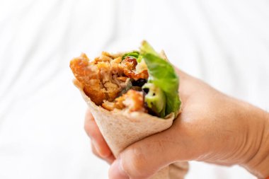 Close up of homemade chicken kebab held in hand.
