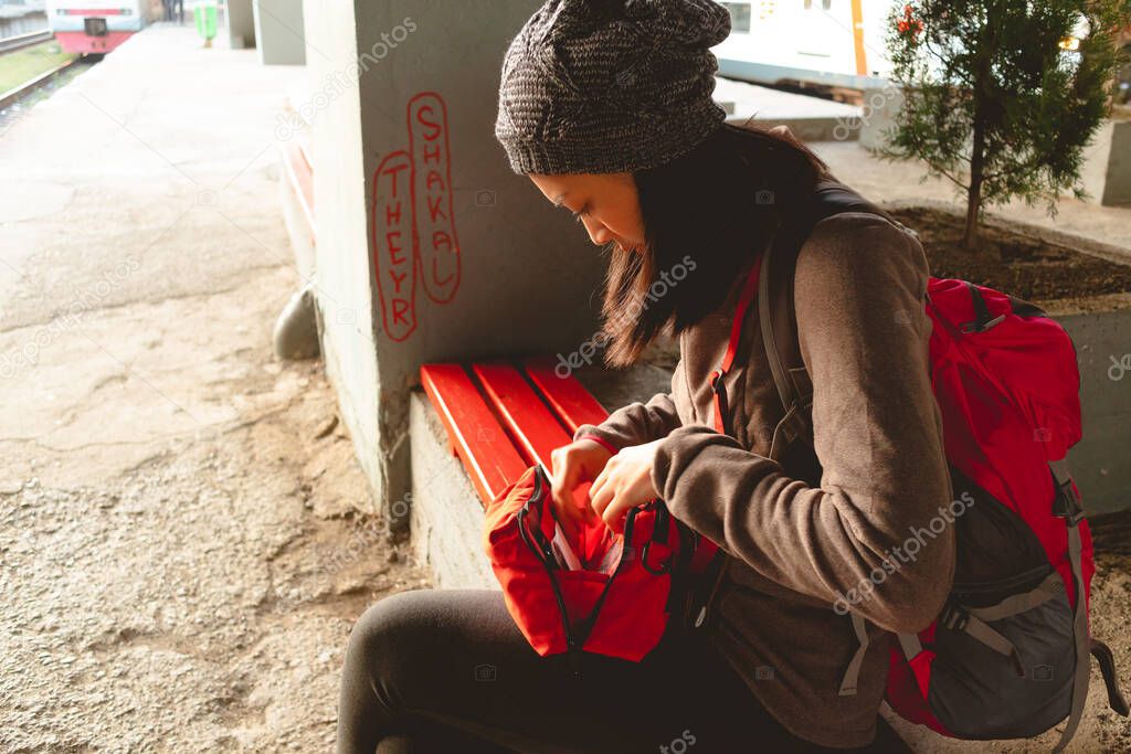 Asian woman is counting money while waiting for the train at the train station.