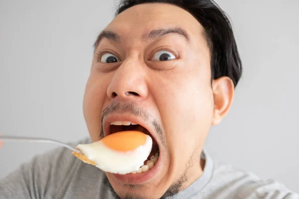 Funny face of man eats fried egg for protein. — Stock Photo, Image