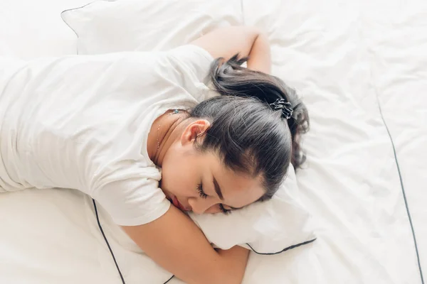Γυναίκα κοιμάται στο λευκό κρεβάτι της στο διαμέρισμα. — Φωτογραφία Αρχείου