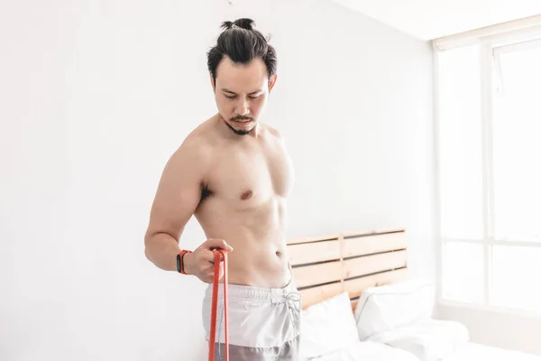 Man stretching zijn spier in concept van workout thuis met weerstand band. — Stockfoto
