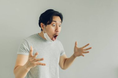 Gri tişörtlü beyaz hijyenik maske takan adamın şok olmuş ve şaşırmış yüzü..