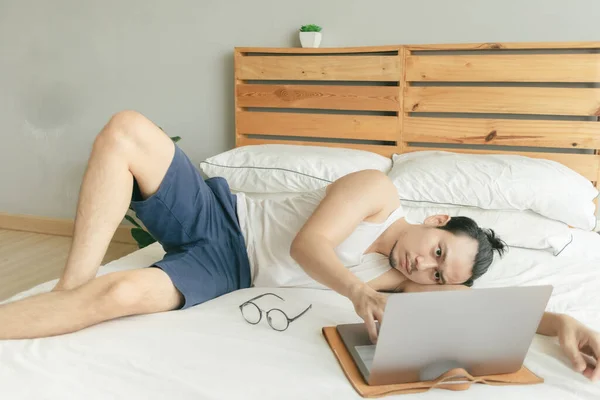 Мужчина работает из дома в очень повседневной одежде и волосах на своей кровати . — стоковое фото