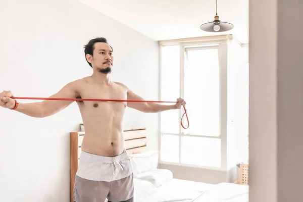 Man stretching zijn spier in concept van workout thuis met weerstand band. — Stockfoto