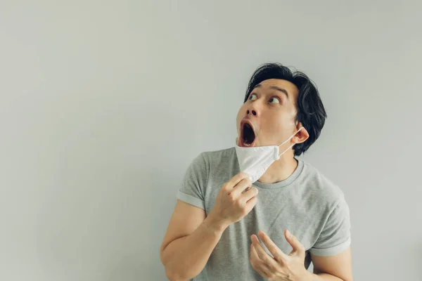 Shocked and surprised face of man wearing white hygienic mask in grey t-shirt. — Stock Photo, Image