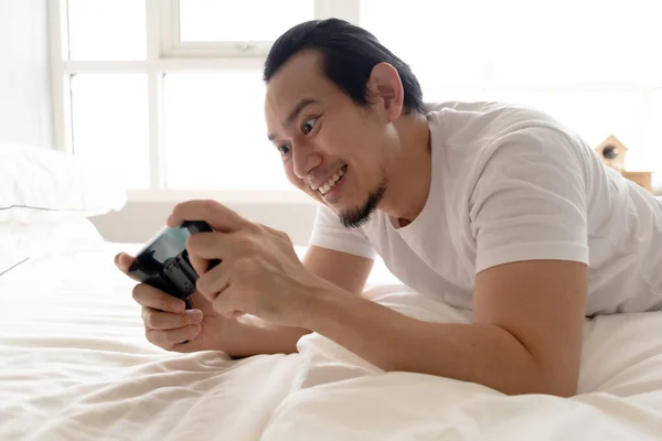 Homem feliz fica em casa e jogar jogo móvel em seu apartamento . — Fotografia de Stock