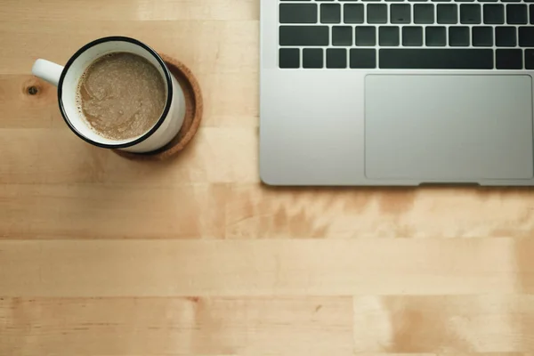Miejsce pracy z laptopem i filiżanką kawy na drewnianym biurku. — Zdjęcie stockowe