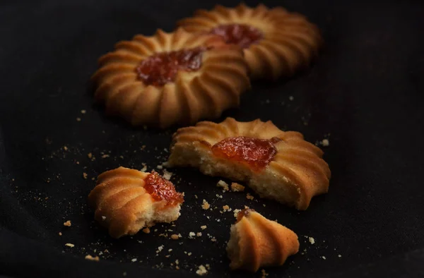 Three cookies with jam wiht crumbs in dark and moody